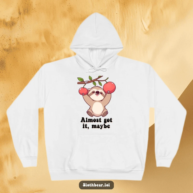 Funny hoodie featuring a baby sloth bear cub comically reaching for a hanging piece of fruit, radiating funny ambition.